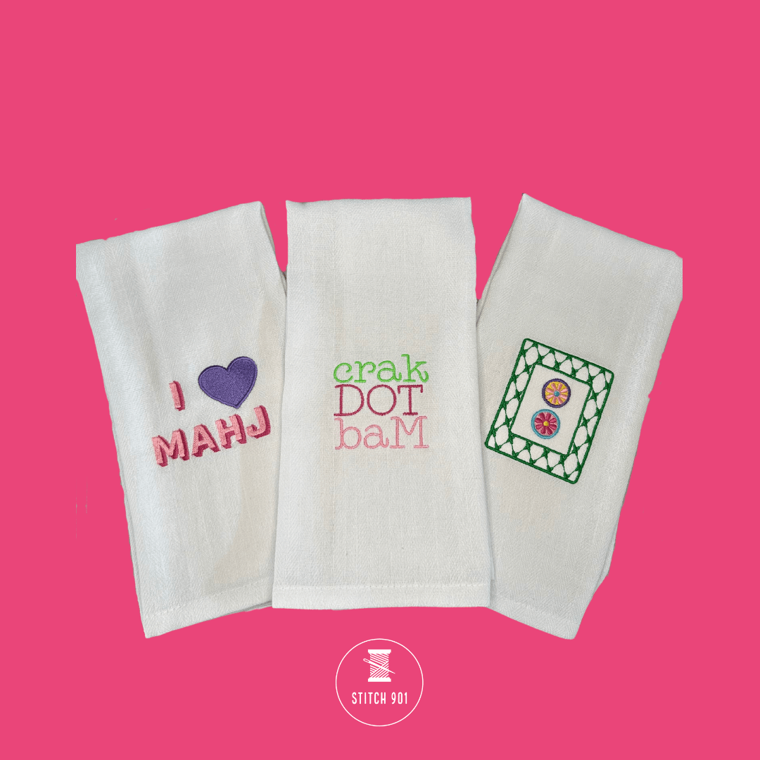 I 💜 MAHJ Tea Towel shown as part of a collection alongside crak dot bam and dot tile embroidered towels