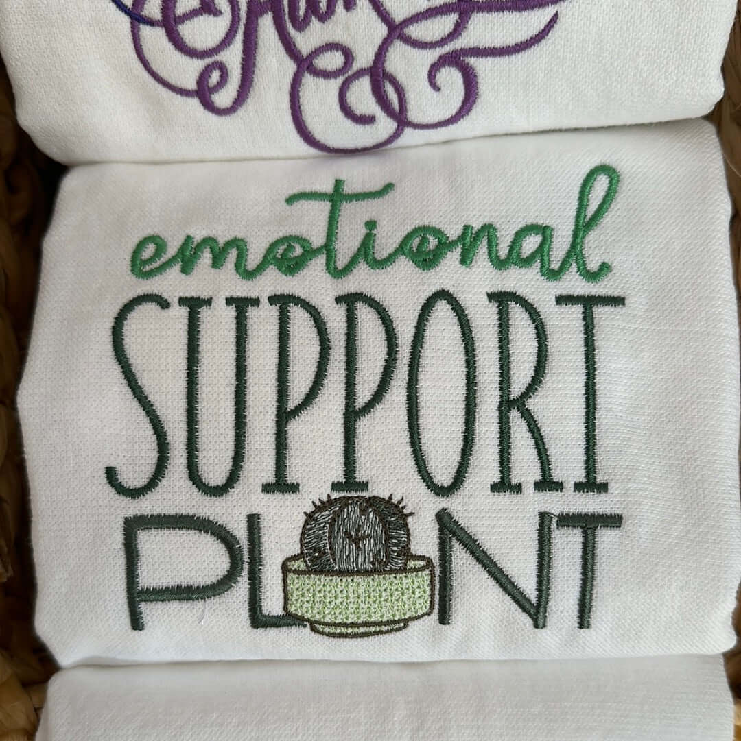 100% cotton tea towel featuring the phrase, “emotional support plant” in lovely shades of green