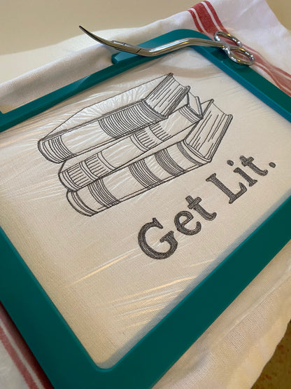 100% cotton tea towel featuring the phrase, “Get Lit” alongside a stack of books. embroidered in gray.
